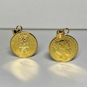 May include: Two gold-coloured pendants, one with a portrait of a woman wearing a crown and the other with a design of a building. Both pendants have text around the edges.