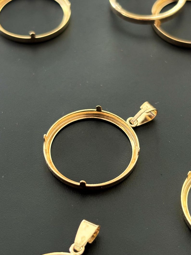 K&ouml;nnte beinhalten: Goldfarbener Metall-M&uuml;nzen-Bezel-Anh&auml;nger mit einer &Ouml;se zum Anbringen einer Kette. Die Einfassung ist f&uuml;r eine runde M&uuml;nze oder ein Medaillon ausgelegt.