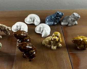 Può includere: Una collezione di 14 piccole figurine in ceramica di vari animali, tra cui un cavallo, un cane, un pesce e un uccello. Le figurine sono dipinte in una varietà di colori, tra cui marrone, bianco, blu e verde.