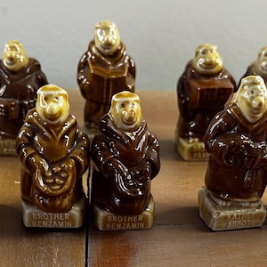 Puede incluir: Colección de figuras de monjes de cerámica en varias poses. Las figuras son principalmente marrones con caras de color canela y están de pie sobre bases rectangulares. Algunos sostienen libros u otros objetos. Las bases tienen los nombres de los monjes.