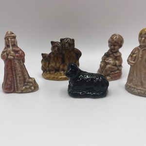 May include: A set of five miniature figurines, including a shepherd, a black sheep, a group of three bears, a girl holding a book, and a boy holding a bird. The figurines are made of ceramic and are painted in various colors.