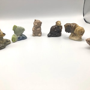 May include: A collection of six small ceramic figurines, including a deer, a fish, a bear, a beaver, a lion, and a bird. The figurines are all hand-painted and have a vintage look.