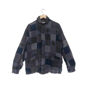 May include: A blue and gray patchwork jacket with a zipper closure and two pockets. The jacket has a stand-up collar and long sleeves.