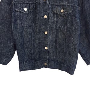 Puede incluir: Una chaqueta vaquera azul oscuro con cierre de botones y dos bolsillos en el pecho. La chaqueta tiene una longitud ligeramente recortada y un estilo cl&aacute;sico.