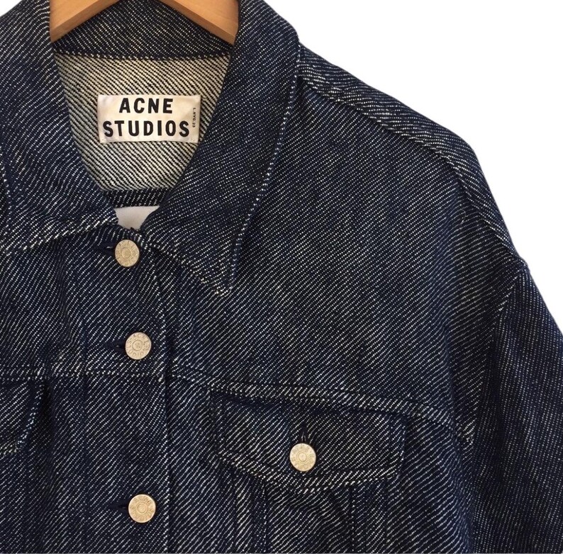 Puede incluir: Una chaqueta vaquera azul oscuro con una etiqueta blanca que dice "Acne Studios".