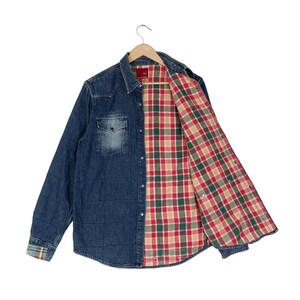 以下が含まれることがあります： キルティング加工が施された長袖のデニムシャツで、胸ポケットが1つ付いています。内側は赤、緑、ベージュのチェック柄の生地で裏打ちされています。シャツのフロントと袖口には、銀色のスナップボタンが付いています。
