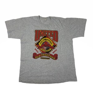 Vintage 80s Manchester United F.C., Red Devil Old Trafford Champion T-Shirt / Größe 23”x27”
