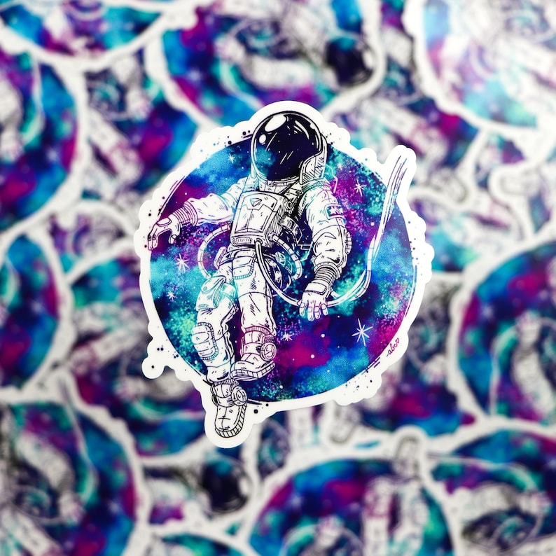 May include: A sticker featuring a black and white illustration of an astronaut floating in space. The astronaut is surrounded by a colorful galaxy with shades of blue, purple, and pink.