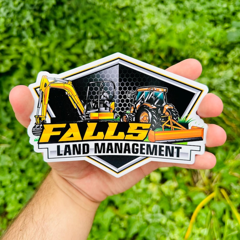 K&ouml;nnte beinhalten: Ein gelber und schwarzer Aufkleber mit einem Logo f&uuml;r Falls Land Management. Das Logo zeigt einen gelben Bagger und einen gelben Traktor vor einem schwarzen Hintergrund mit einem Wabenmuster.