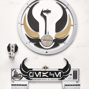 May include: A set of three-dimensional wall art pieces featuring a circular emblem, a small ring, and a rectangular sign. The emblem has black, gold, and silver elements. The sign reads "CIVIK'M PEACE & JUSTICE" in black and white.