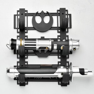 May include: Black wall mount with a Rebel Alliance symbol and two slots for lightsabers. The lightsabers are silver and black with gold accents.