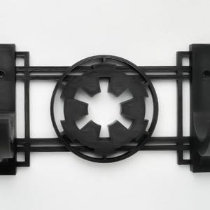 May include: Black wall-mounted hook with two hooks and a stylized Imperial symbol from Star Wars in the center.