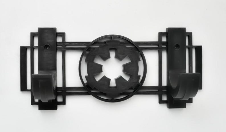 May include: Black wall-mounted hook with two hooks and a stylized Imperial symbol from Star Wars in the center.