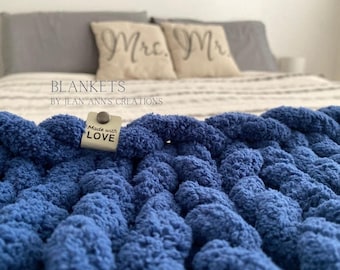 Puede incluir: Una manta de punto azul gruesa con una etiqueta que dice "Made with Love" en una cama con dos almohadas que dicen "Mr. Mr."