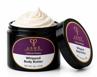 Pode incluir: Um frasco preto de ASHE Spiritual Skincare Whipped Body Butter com a tampa aberta. O frasco contém um redemoinho de manteiga corporal branca. O rótulo diz "7 African Powers" e "NET WT. 226g".