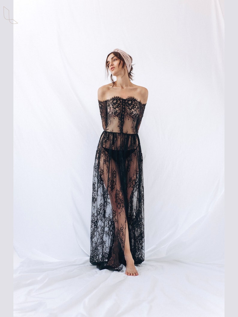 May include: A black lace maxi dress with an off-the-shoulder neckline and long sleeves. The dress is sheer and has a fitted bodice and a flowing skirt.