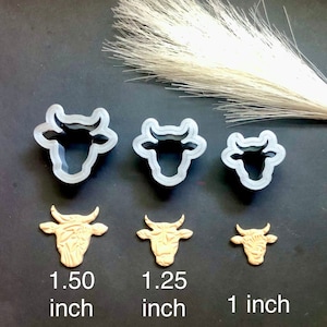 Puede incluir: Tres cortadores de galletas con forma de cabeza de vaca y tres figuras de arcilla con forma de cabeza de vaca. Los cortadores son de plástico transparente y las figuras de arcilla son de color beige. El más grande mide 3,81 cm.
