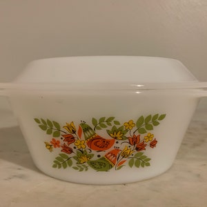 May include: White ceramic casserole dish with a lid. The dish has a floral design with green leaves, orange and yellow flowers, and two birds with orange, yellow, and green accents.