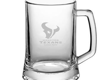 May include: A clear glass beer stein with a Houston Texans logo and the words "Houston Texans" and "Custom Name" etched on the front.