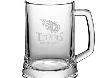 May include: A clear glass beer stein with a Tennessee Titans logo and the text "Tennessee Titans" and "Custom Name" etched on the front.