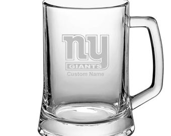 May include: A clear glass beer stein with a New York Giants logo and the text "Custom Name" etched on the front.
