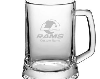 May include: A clear glass beer mug with a Los Angeles Rams logo and the text "RAMS" and "Custom Name" etched on the front.