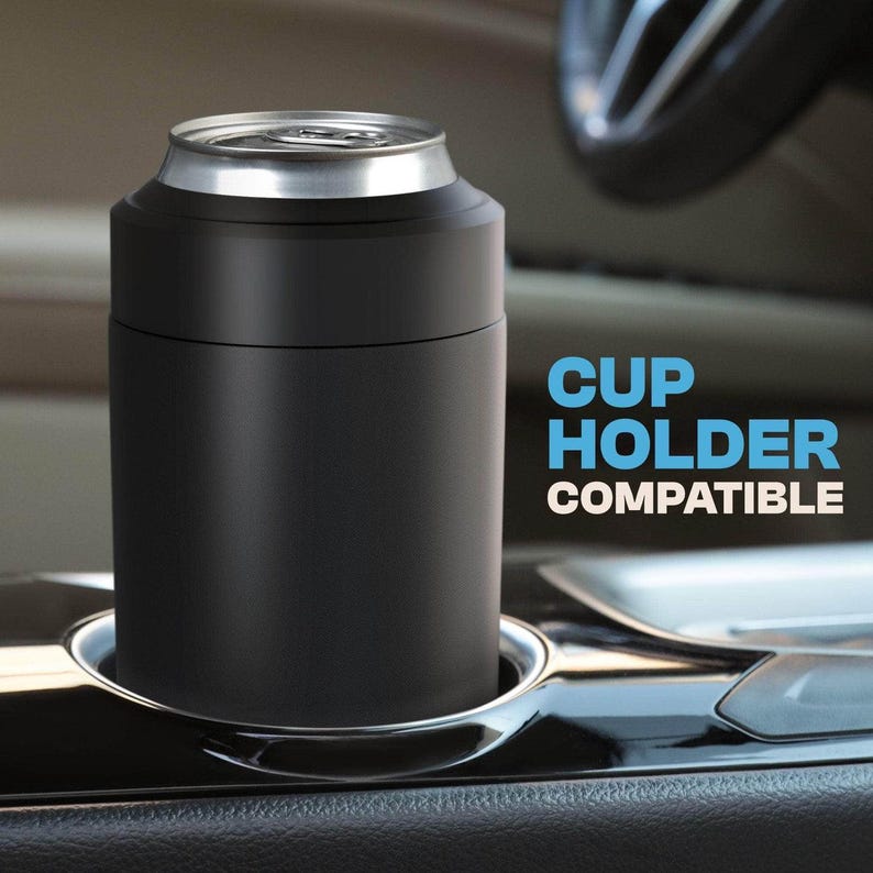 May include: A black can cooler with a silver rim, designed to fit in a car cup holder. The text "CUP HOLDER COMPATIBLE" is printed in blue and white on the right side of the image. The cooler is cylindrical.