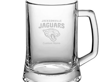May include: A clear glass beer mug with a Jacksonville Jaguars logo and the text "Jacksonville Jaguars" and "Custom Name" etched on the front.