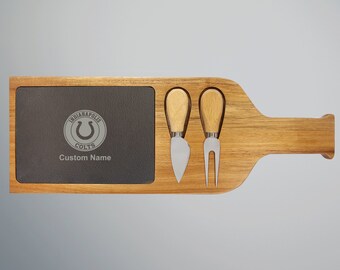 May include: Wooden cheese board shaped like a wine bottle with a slate serving area. The slate has a gray Indianapolis Colts logo with the text "Indianapolis Colts" and "Custom Name". The board includes two cheese knives with wooden handles.
