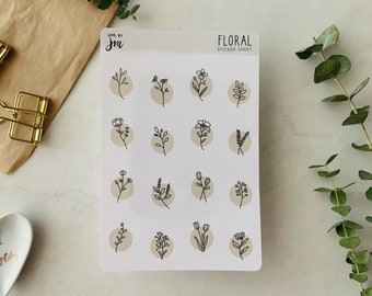 May include: A sheet of floral stickers featuring black ink botanical illustrations on beige circles. The sheet is labelled "FLORAL STICKER SHEET" and includes the "Love by JM" logo. Gold binder clips and a heart-shaped dish are also visible.