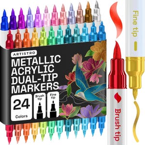 Puede incluir: Un juego de 24 marcadores acrílicos metálicos de doble punta Artistro en una caja negra con una ilustración de un pájaro y flores. Los marcadores tienen puntas de pincel y finas en varios colores metálicos. Se muestran dos marcadores.
