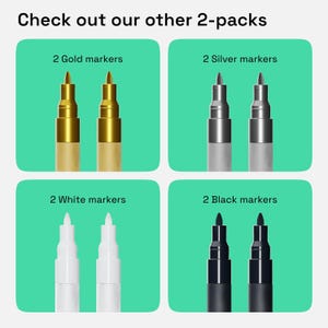May include: Four sets of two markers, each set featuring a different color: gold, silver, white, and black. The markers are arranged in a grid pattern on a green background. The text "Check out our other 2-packs" is at the top of the image.