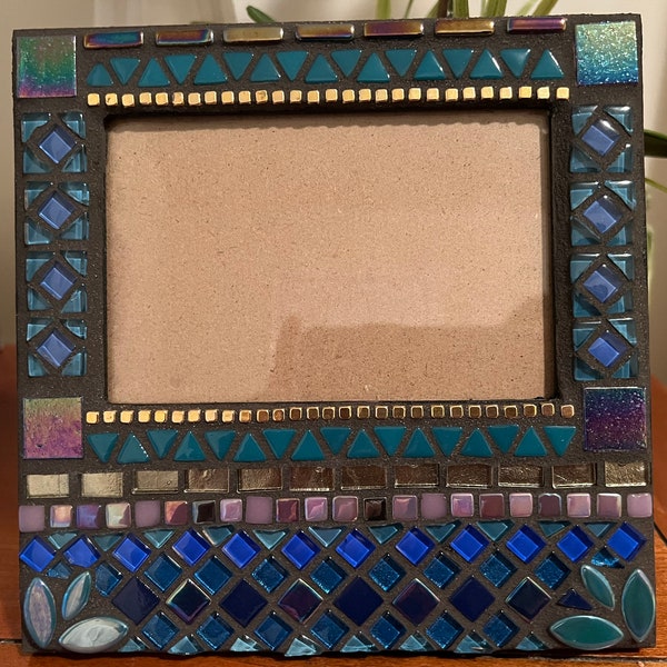 Mosaic picture frame in iridescent jewel tones. Frame is 8x8 and holds a 5.5x3.5 inch picture. Colors are teal, cobalt, gold, and purple.