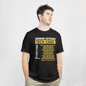 May include: Black t-shirt with the text "SENIOR CITIZEN TECH CODE" in yellow and white. The shirt lists humorous tech-related phrases such as "Still Searching for Dentures" and "Memory Not Found".