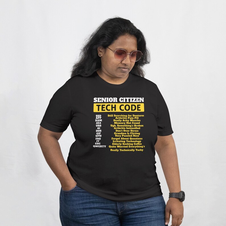 May include: Black t-shirt with the text "SENIOR CITIZEN TECH CODE" in white and yellow. The shirt lists humorous tech-related phrases like "Still Searching for Dentures" and "Memory Not Found". The shirt is a humorous gift idea.