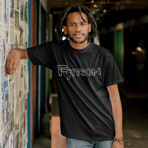 Puede incluir: Una camiseta negra con un dise&ntilde;o gr&aacute;fico blanco que dice "PYTRON".