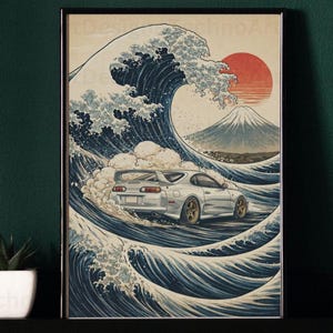 May include: Framed print depicting a white sports car navigating a large wave, with a red sun and mountain in the background. The style is inspired by traditional Japanese art. The print is in a black frame.