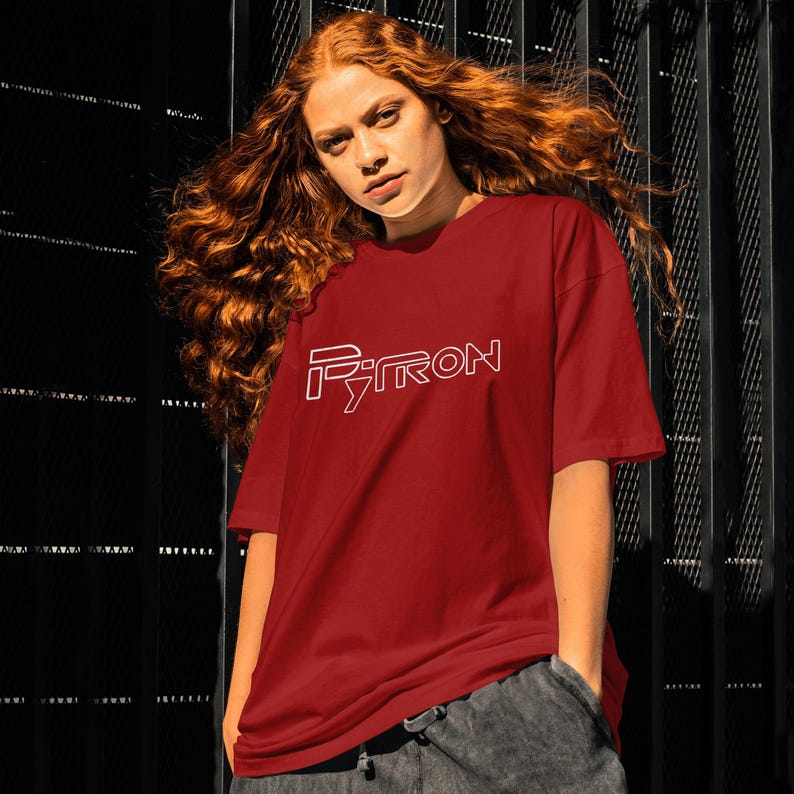 Puede incluir: Una camiseta roja con un contorno blanco de la palabra "PYTRON" en la parte delantera.