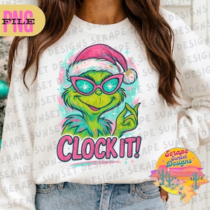 May include: White sweatshirt featuring a green cartoon character wearing a pink Santa hat and sunglasses. The text "CLOCK IT!" is in pink. The design has a turquoise and pink color scheme.