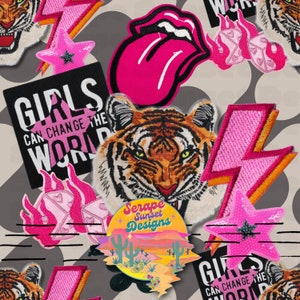Pode incluir: Uma coleção de patches termocolantes coloridos com um tigre, uma língua, raios, estrelas e um slogan que diz "As meninas podem mudar o mundo". Os patches estão sobre um fundo cinza com listras pretas e brancas.