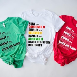 May include: Three t-shirts in green, white, and red with the text "RUBY 1960 CONCEIVED IT SHIRLEY 1972 BELIEVED IT KAMALA 2024 ACHIEVED IT BLACK HER-STORY CONTINUES" printed in black, yellow, and green.