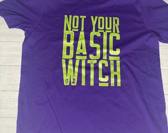 May include: Purple t-shirt with the text "NOT YOUR BASIC WITCH" in green.