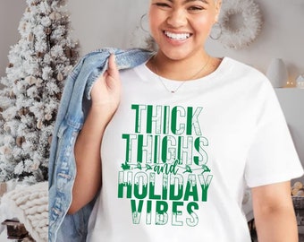 Puede incluir: Camiseta blanca con texto verde que dice "Thick Thighs and Holiday Vibes".
