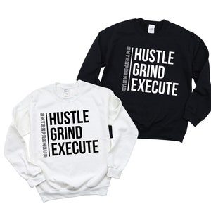 May include: Two sweatshirts, one white and one black, with the words "Hustle Grind Execute" and "Entrepreneur" printed vertically on the side.