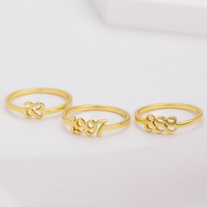 May include: Three gold rings with different numbers engraved on them. The rings are 1997, 888, and 23.