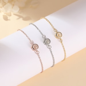 Puede incluir: Tres delicados brazaletes con un solo encanto redondo de perla en el centro de cada uno. Los brazaletes son de oro, plata y oro rosa.