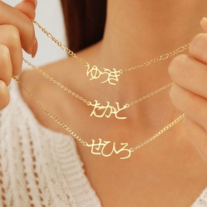 Könnte beinhalten: Drei goldene Halsketten mit japanischen Schriftzeichen. Die Zeichen sind "ゆめ", "むね" und "せひる".