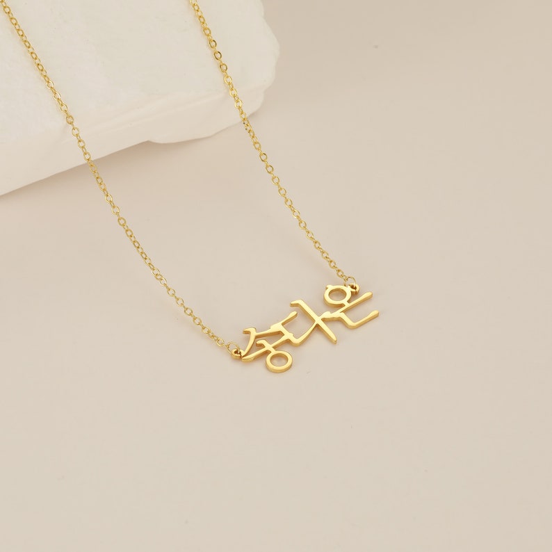 May include: A gold chain necklace with a pendant featuring the Korean word "Freedom" in Hangul.