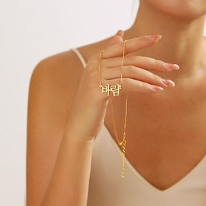 May include: A gold chain necklace with a pendant that says "바람" in Korean script.