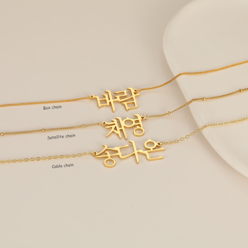 May include: Three gold necklaces with different chain styles: box chain, satellite chain, and cable chain. Each necklace features a pendant with Korean text.